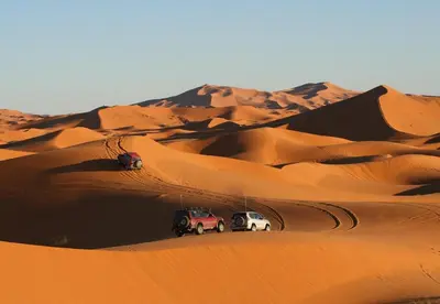 two cars parked in the sand in the desert at Sands Charm Luxury Camp in Merzouga