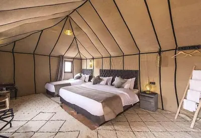 a bedroom with two beds in a tent at Sands Charm Luxury Camp in Merzouga