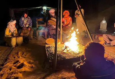 a group of people sitting around a fire at Sands Charm Luxury Camp in Merzouga