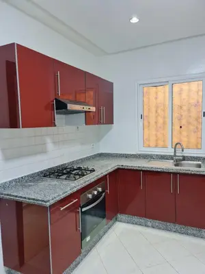 an empty kitchen with red cabinets and a sink at Fes Magic Apartment - With Swimming pool in Fès