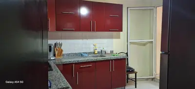 a kitchen with red cabinets and a sink at Fes Magic Apartment - With Swimming pool in Fès