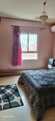 a bedroom with a bed and a window and a rug at Fes Magic Apartment - With Swimming pool in Fès