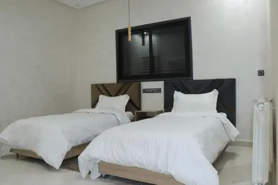 two beds in a room with a tv on the wall at VANA hôtel in Midelt