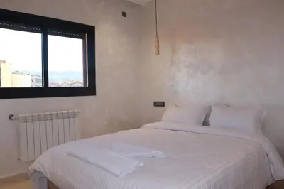 a bedroom with a bed with white sheets and a window at VANA hôtel in Midelt