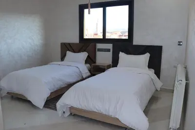 a bedroom with two beds with white sheets and a window at VANA hôtel in Midelt