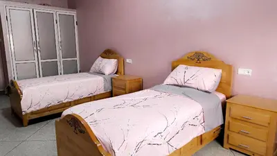 a bedroom with two beds and a dresser and cabinets at Home Amazigh Serenity in Tinerhir