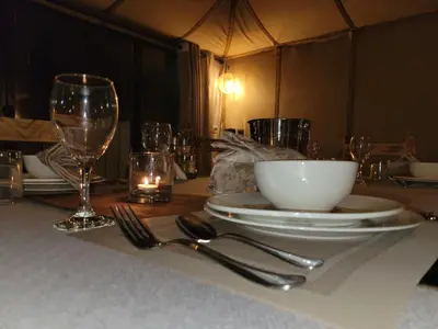 a table with a plate and a bowl and wine glasses at Golden Gate Luxury in Merzouga