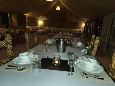 a table in a tent with plates and wine glasses at Golden Gate Luxury in Merzouga