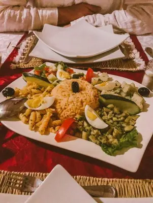 a plate of food with rice and vegetables on a table at Merzouga Dunes Camp in Merzouga