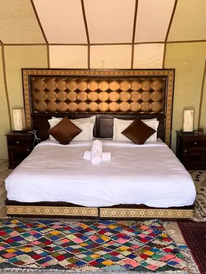 a bedroom with a large bed with a large headboard at Merzouga Dunes Camp in Merzouga