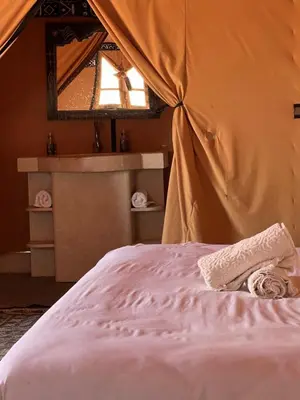 a bed in a tent with a towel on it at Merzouga Dunes Camp in Merzouga