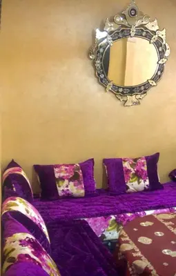 a purple bed with purple pillows and a mirror at منزل شامة in Moulay Yacoub