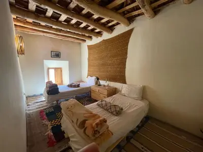 a room with two beds and a dog on a couch at Gite d'étape Chez Brahim in Kalaat MGouna