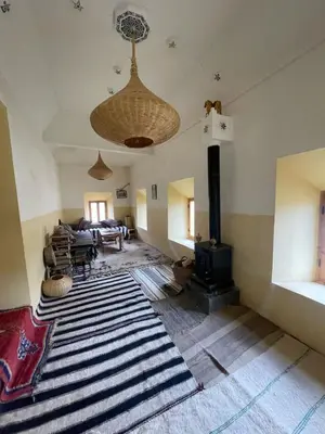 a living room with a fireplace and a rug at Gite d'étape Chez Brahim in Kalaat MGouna