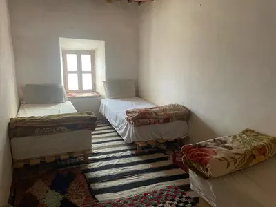 a room with three beds and a window at Gite d'étape Chez Brahim in Kalaat MGouna