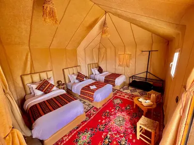 two beds in a room with a red rug at Paradise Luxury Camp in Merzouga