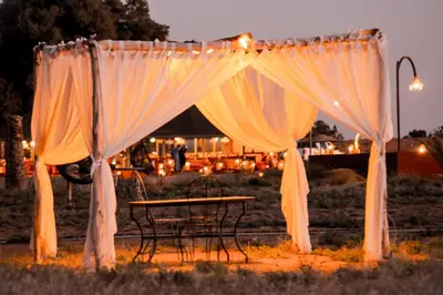 a table and chairs under a tent with curtains at Paradise Luxury Camp in Merzouga