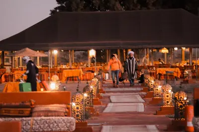 a group of people walking down a walkway with lights at Paradise Luxury Camp in Merzouga
