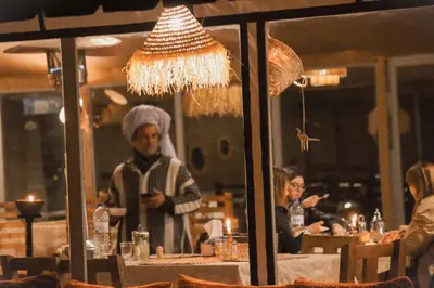 a man standing at a table in a restaurant at Paradise Luxury Camp in Merzouga