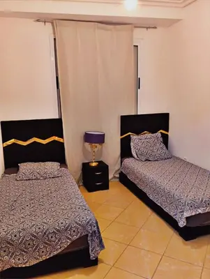 a bedroom with two beds and a lamp in it at Gîte du lac chez bennouri in Telouet