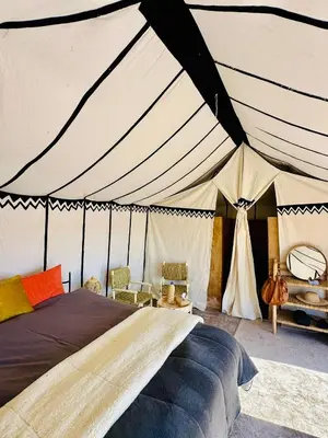 a bedroom with a tent with a bed and chairs at Nomademoi Luxury Camp in El Gouera