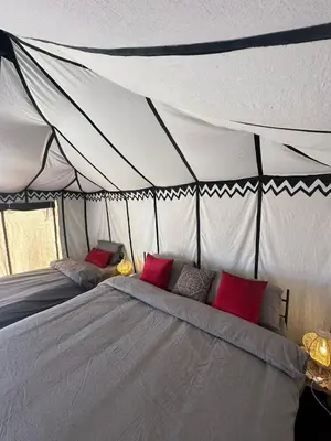 a bed in a tent with red pillows on it at Nomademoi Luxury Camp in El Gouera