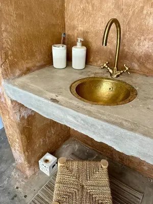 a bathroom with a gold sink and two white containers at Nomademoi Luxury Camp in El Gouera
