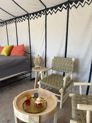 a room with a bed and a table and a chair at Nomademoi Luxury Camp in El Gouera