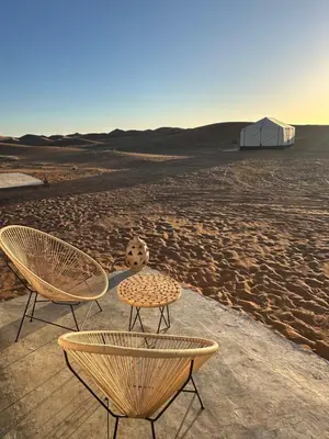 two chairs and a table in the desert at Nomademoi Luxury Camp in El Gouera