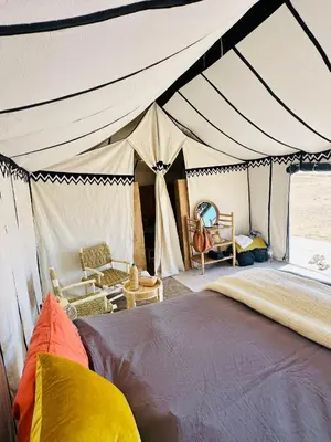 a bedroom with a tent with a bed and a chair at Nomademoi Luxury Camp in El Gouera