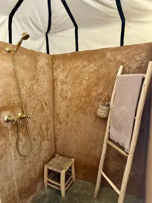 a bathroom with a shower and a chair and a towel at Nomademoi Luxury Camp in El Gouera