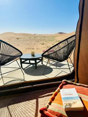 a room with two chairs and a table in the desert at Nomademoi Luxury Camp in El Gouera