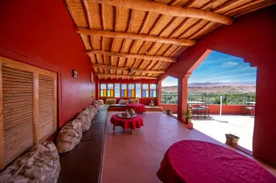 a living room with a red wall with a couch and a table at Kasbah Tasseurte in Kalaat MGouna