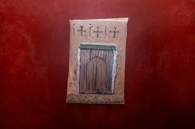 a wooden door on a red wall with writing on it at Kasbah Tasseurte in Kalaat MGouna