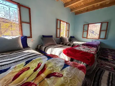 a room with four beds in a room with windows at Gite Megdaz Ouhadouch in Megdaz
