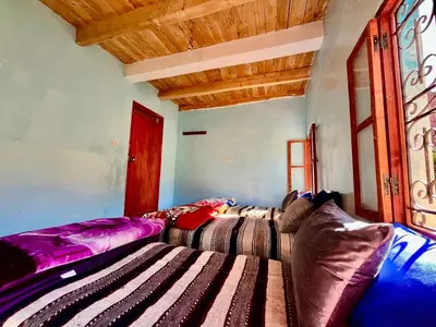 a living room with two beds and a window at Gite Megdaz Ouhadouch in Megdaz