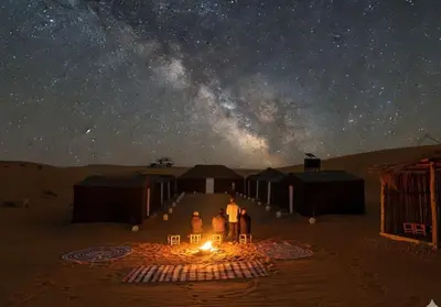 a group of people standing in the desert under a starry sky at Merzouga Camp & 4x4 Transfeer Include in Merzouga
