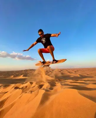 a man riding a surfboard in the desert at Merzouga Camp & 4x4 Transfeer Include in Merzouga