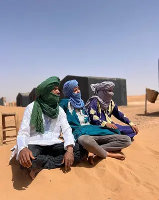 four people sitting on the sand in the desert at Merzouga Camp & 4x4 Transfeer Include in Merzouga