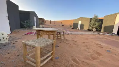 a group of tables and stools in the desert at Merzouga Camp & 4x4 Transfeer Include in Merzouga
