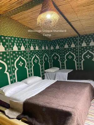 a bedroom with a bed and a green wall at Merzouga Camp & 4x4 Transfeer Include in Merzouga