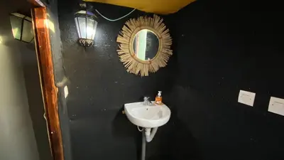 a bathroom with a sink and a mirror on a black wall at Merzouga Camp & 4x4 Transfeer Include in Merzouga