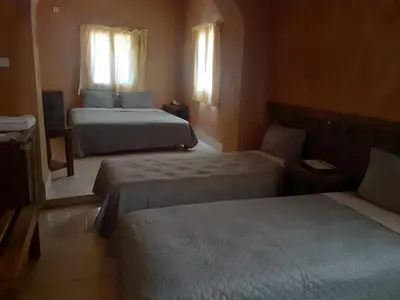 a hotel room with two beds and two windows at Hotel Ksar Kaissar in Kalaat MGouna