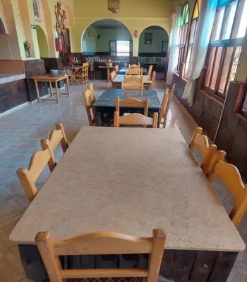 a large wooden table and chairs in a room at Hotel Ksar Kaissar in Kalaat MGouna