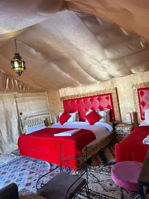 a bedroom with a red bed in a tent at Dune Glamp Camp in Merzouga