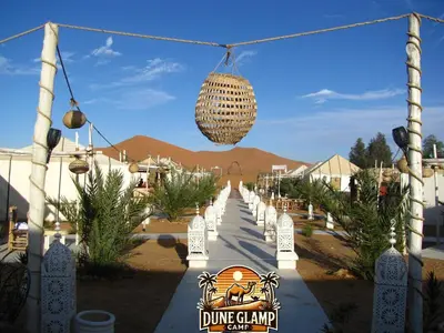 a walkway in a desert with a chandelier at Dune Glamp Camp in Merzouga