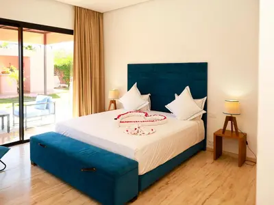 a bedroom with a large bed with a blue headboard at Villa des iris Domaines NAJMA in Marrakech