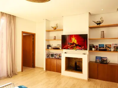 a living room with a fireplace and a flat screen tv at Villa des iris Domaines NAJMA in Marrakech