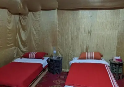 two beds in a room with red pillows at Sahara horizon Camp in Merzouga