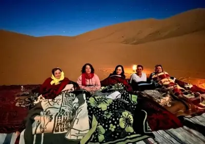 a group of women sitting on beds in the desert at Sahara horizon Camp in Merzouga